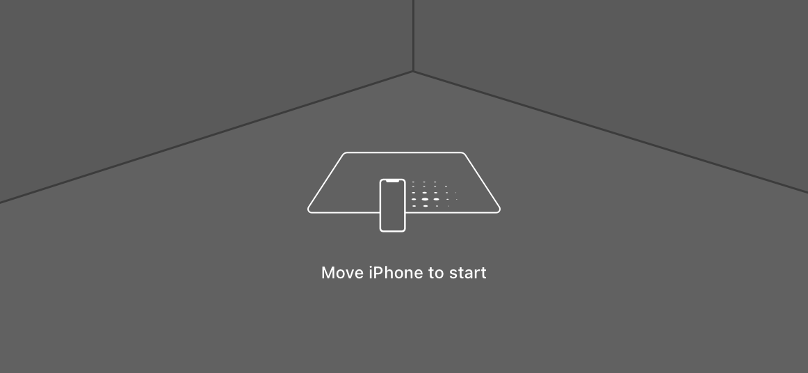 An illustration of an iPhone screen showing the corner of a room viewed through the camera. On the screen is a translucent overlay containing the surface-detection indicator. The indicator is a white square with rounded corners projected into the 3D space. A small iPhone is shown scanning back and forth along the base of the square. A circle of dots trailing the iPhone emphasizes the movement.