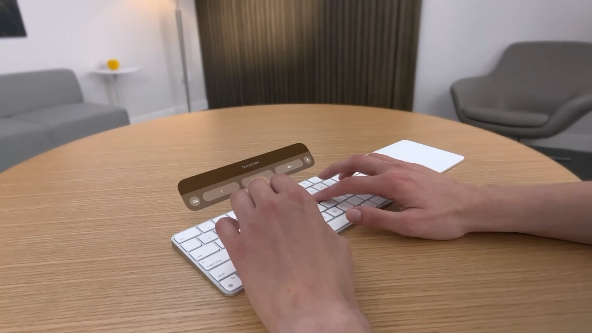 A recording that shows two hands typing on a physical keyboard while the person runs an app in visionOS. A virtual window is visible above the physical keyboard, and displays the entered text and suggestions.